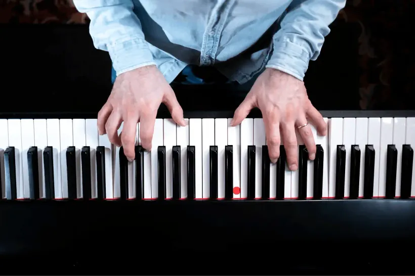 Vue du dessus des mains de Cyrille sur les touches d’un clavier