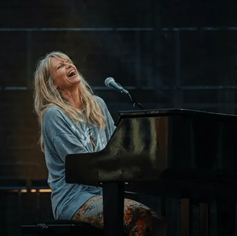 Une MyPianiste chante en s’accompagnant au piano, visiblement heureuse de jouer