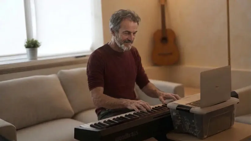 Un MyPianiste joue sur son clavier chez lui, dans son salon, le sourire aux lèvres